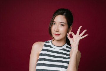 Portrait of beautiful asian woman with ok gesture isolate on red background.