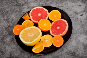 Cut citrus on a plate, Various citrus fruits, Citrus on a concrete background, copy space