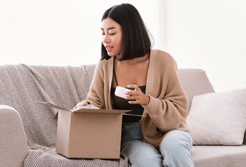 Asian woman unpacking parcel with beauty box