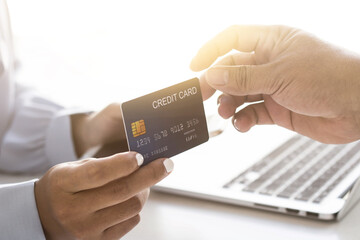 Woman's hand is giving a card to a man's hand, using credit cards to pay online.