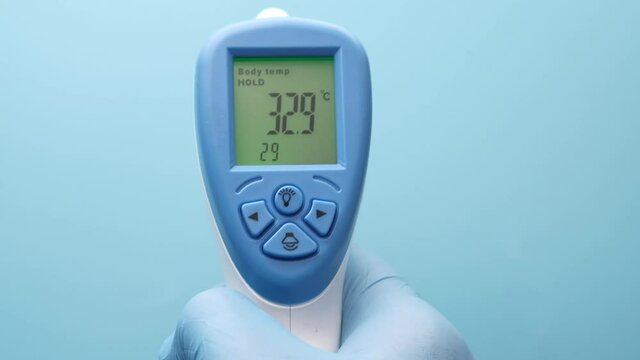 Hand holding infrared thermometer to measuring temperature.