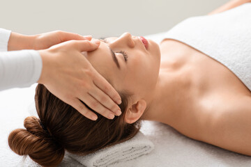 Obraz na płótnie Canvas Spa attendant making healing head massage for young beautiful woman