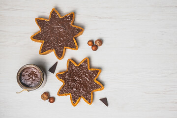 Homemade hazelnut chocolate butter in a jar and spread on star shaped pieces of pandoro panettone.