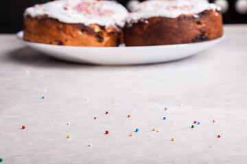 Close-up of confetti - red, yellow, pink, blue and green in a round shape, scattered on a white kitchen table while decorating an Easter cake - a traditional confectionery decoration.
