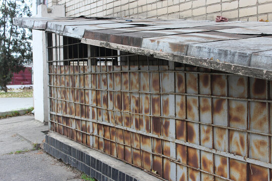 The exit is visible on the side facade of the residential building
 from an air-raid shelter fenced with a metal grate and unpainted rusting sheet. Buildings of the 70s of the 20th century Soviet Unio