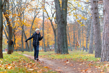 Fototapeta premium teen girl and boy running through the park and enjoys autumn, beautiful nature with yellow leaves