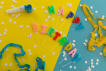 Happy birthday candles with confetti and party streamers on blue and yellow