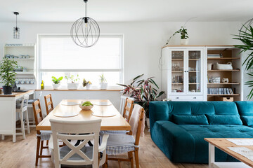 Interior of living room with sofa, table and chairs and big window. White scandinavian design in dining room. Modern apartment. Nobody