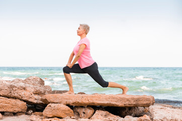 Fototapeta na wymiar Side view of middle aged woman doing yoga on a beach