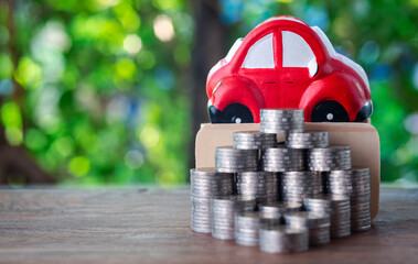 The red car was behind the pile of coins, all on the wooden table. Money-saving ideas