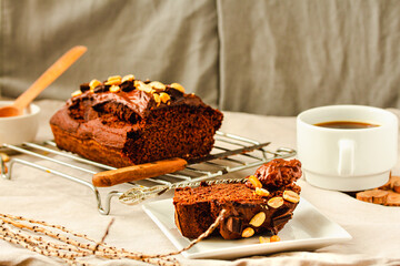 Chocolate cake and slice Spoon with tasty chocolate cream and nuts on on a linen cloth background.Cup of coffee and dessert concept