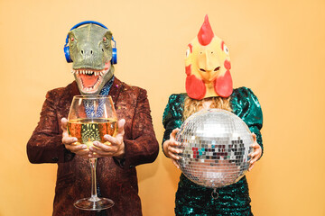 Crazy young couple having fun for new year's eve party wearing t-rex and chicken mask - Fashion...