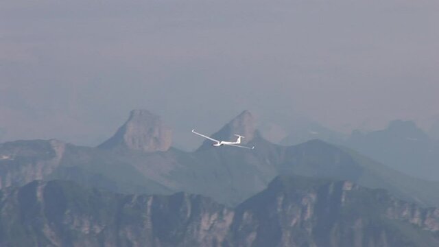 A glider in the sky in front of the swiss mountains