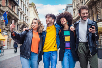 Group of friends tourist walking together hugging outdoors in the city downtown sightseeing having...