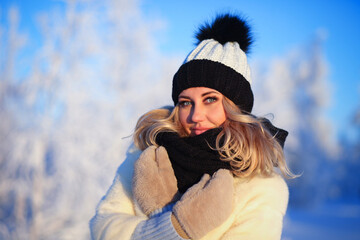 Young woman in a warm knitted hat and a snood in the winter forest