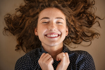 Joyful young woman lying on the floor and laughing