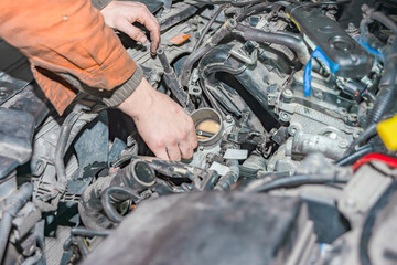 A young guy with dirty hands put the throttle to the engine.