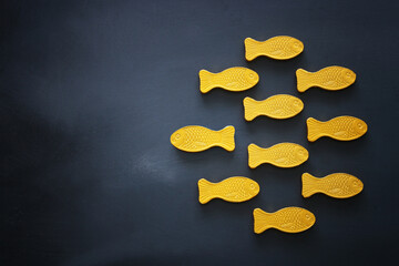 different fish swimming opposite way of identical ones. Courage and success concept. Blackboard background.