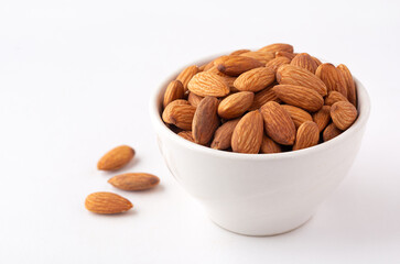 Bowl of raw almonds on a white background with copy space