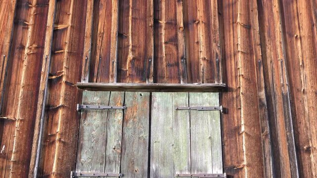 Old farmhouse, barn, wooden front wall with window, in the countryside of Wildhaus, St Gallen, Switzerland. Detail of old traditional rural architecture, alpine cabin in Switzerland.