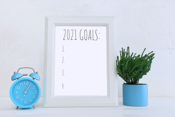 Business concept of top view 2021 goals list over frame, home plant over wooden desk