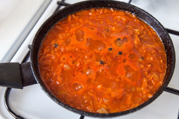 Homemade Tomato Sauce with vegetables simmering in frying pan on stove