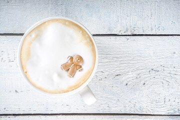 Coffee Latte or Hot Chocolate Mug with Funny Little Marshmallows in Gingerbread Cookie Forms - Gingerbread man, Snowflake, Christmas Tree Toys. Cute and Cozy Winter Drink Background, cup in Woman Hand