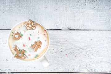 Coffee Latte or Hot Chocolate Mug with Funny Little Marshmallows in Gingerbread Cookie Forms - Gingerbread man, Snowflake, Christmas Tree Toys. Cute and Cozy Winter Drink Background, cup in Woman Hand