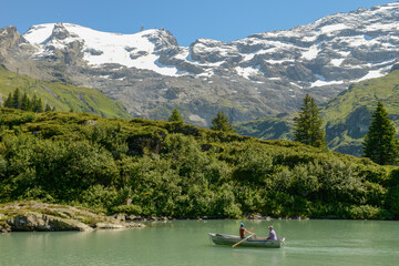 Fototapeta na wymiar Tourists rowing in their boat at lake Truebsee above Engelberg on the Swiss Alps