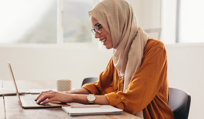Businesswoman with hijab writing on the laptop