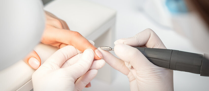 Manicurist removes nail polish uses the electric machine of the nail file during manicure