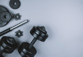 Obraz na płótnie Canvas Top view of black dumbbells and different weight plates with barbell on grey background. Flat lay.