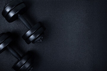Naklejka na ściany i meble Top view of black dumbbells weights on textured mat background. Flat lay.
