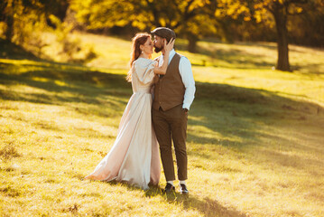 Fototapeta premium Photo of hispter couple. Groom tenderly kissing bride surrounding by nature and sunlights .