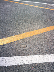 White and red line road markings on dry, grainy asphalt.