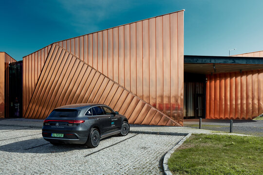 Zory / Poland-10.06.2020: Electric Mercedes EQC standing against the golden wall of the Fire Museum. The car has a 408HP engine and accelerates 0-100 km / h in 5.1 seconds. Range (WLTP) 369-414 km