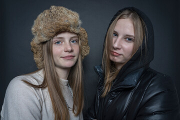Fototapeta premium Portrait of two beautiful young girls indoors on a black background