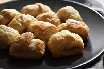 Sausage rolls on a black plate.