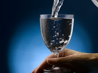 Pouring water into a clear glass. Close-up