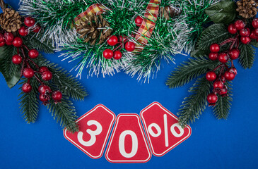 Big sales 30%, thirty percents with Christmas wreath on a dark blue  background, top view, copy space, flat layout. Christmas big sale.