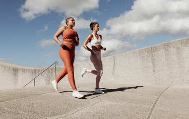 Two women jogging together - obrazy, fototapety, plakaty