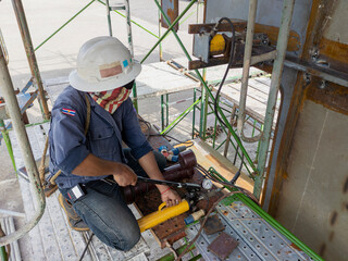 Workers are using hydraulic jacks to bending steel plate after welding at industrial factory.