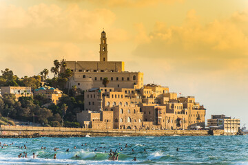 Fototapeta na wymiar Old Jaffa city, old port and coastal line of Tel Aviv under sunset and lots of tourists are swimming and surfing at the Mediterranean sea.