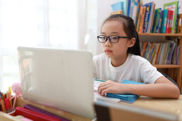 Portrait of 11-year-old teenager Asian girl using laptop for online study during homeschooling at home