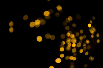 Bokeh on a black background for use in the photo editor. Beautiful bright curly bokeh. Magic background for new year and Christmas. Banner with yellow unfocused lights garlands in the form of circles.