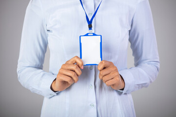Young smiling woman holding a blank business card. Businesswoman with blank business card. Woman holding, showing corporate id pass, name tag on white background
