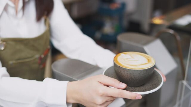 Closeup slow motion barista hands serving beautiful latte art coffee.
