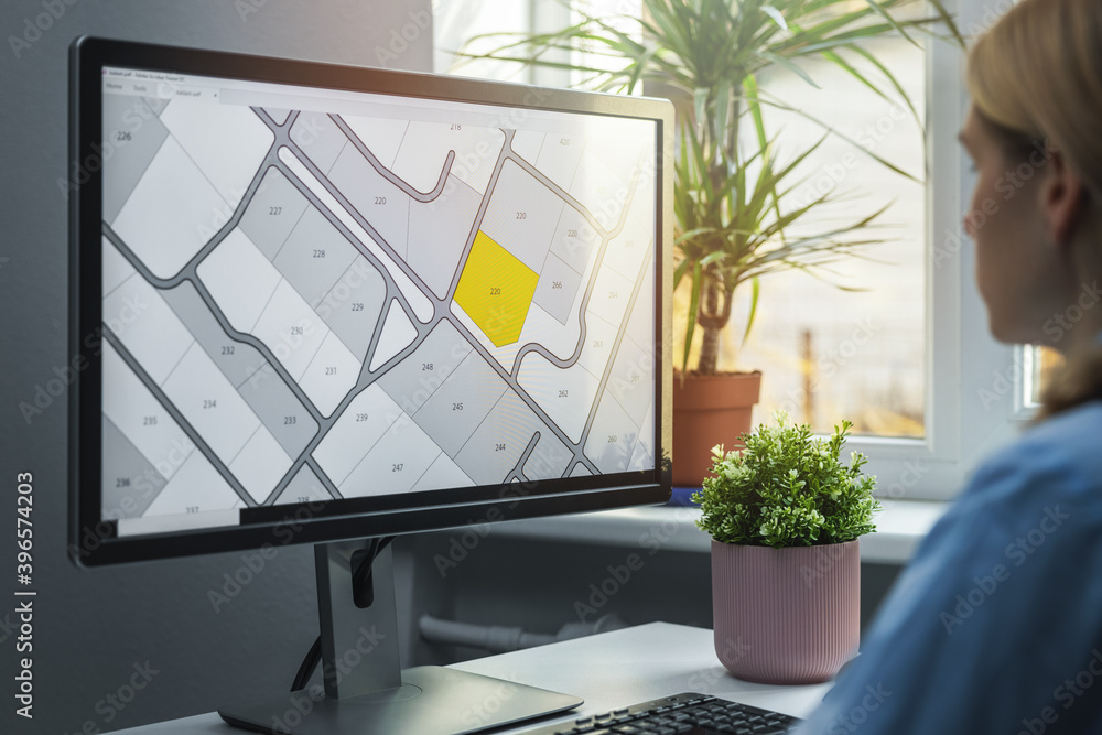 Wall mural woman working with digital land registry database on computer in office
