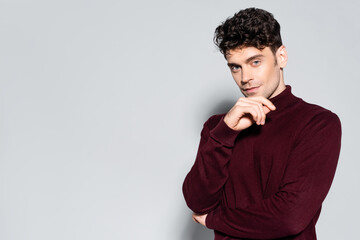  man in burgundy turtleneck jumper posing isolated on grey