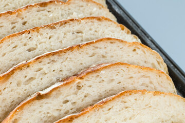 Freshly homemade bread sliced on a baking paper in a baking tray, light and airy inside with a crunchy rustic crust.